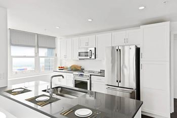 A modern kitchen with a stainless steel refrigerator and a window overlooking the city.